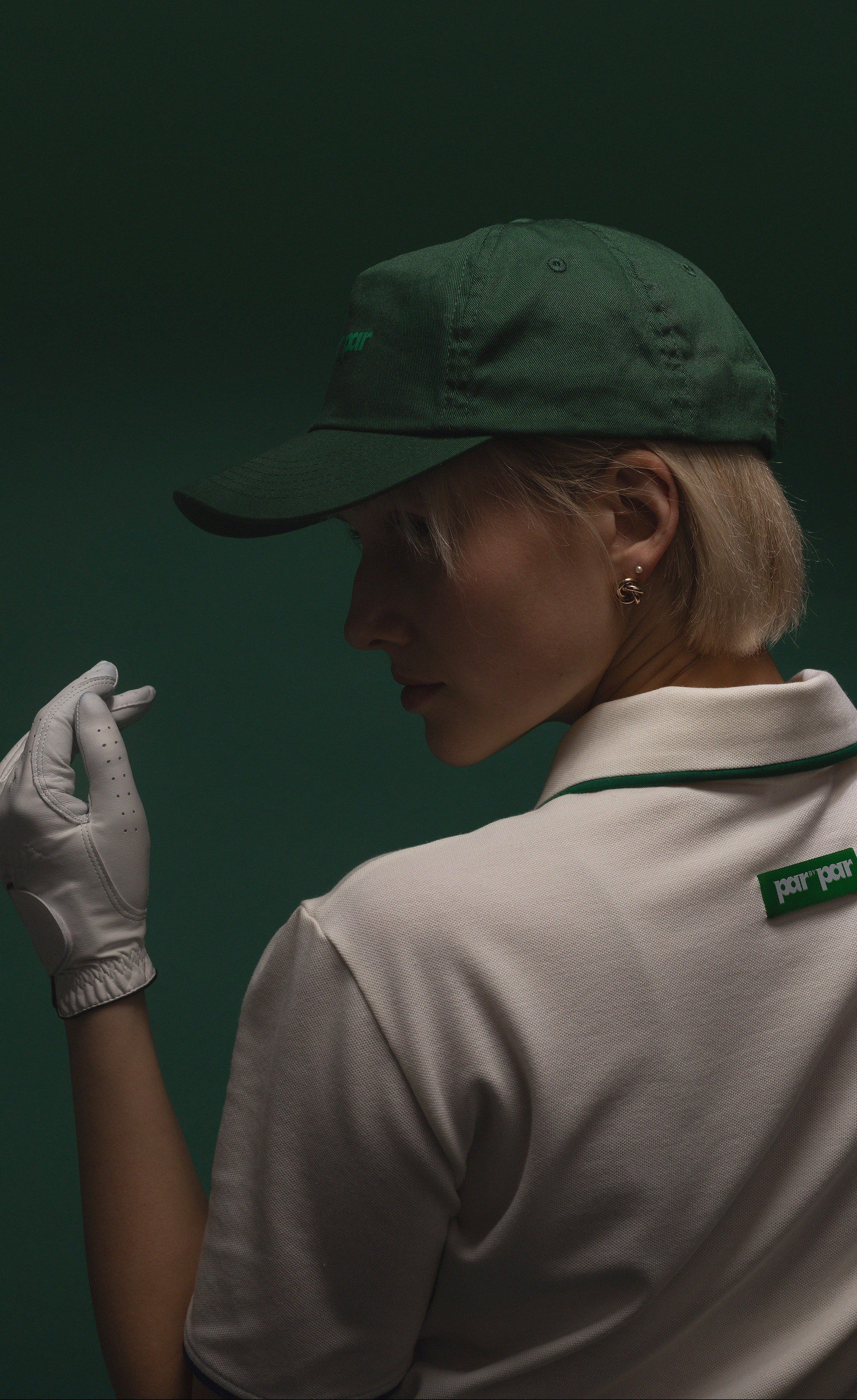 Woman wearing Par by Par white polo shirt and green golf cap with leather golf glove